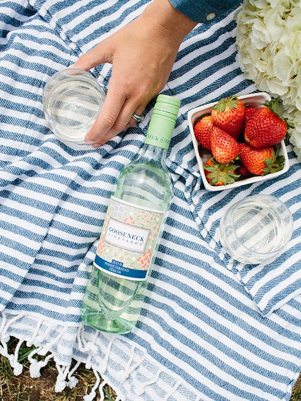 Bottle of Gooseneck Vineyards Pinot Grigio on a blanket with strawberries